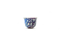 Decorative glass cup with blue and white pattern on a white background