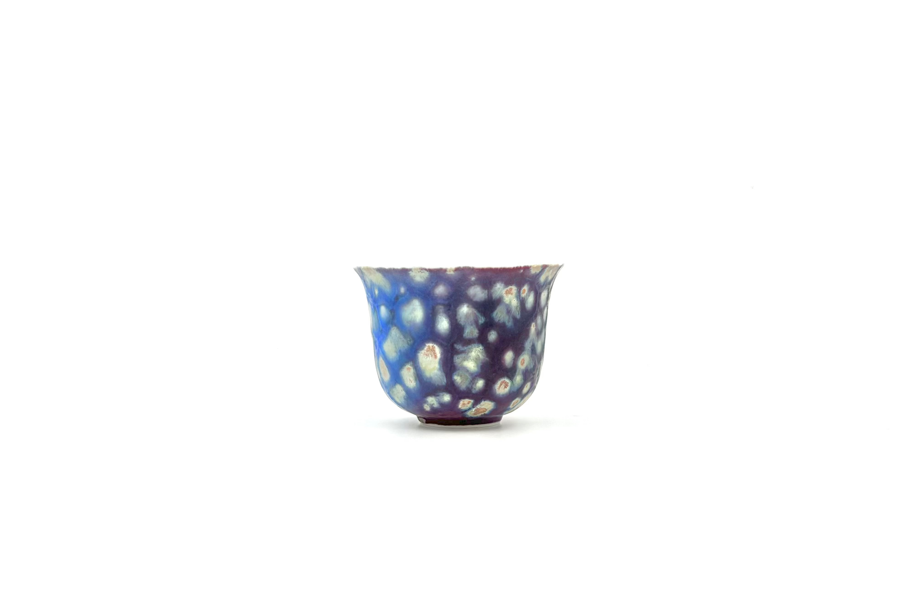 Decorative glass cup with blue and white pattern on a white background