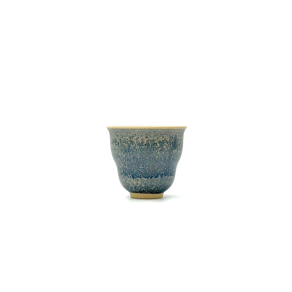 Ceramic cup with blue speckled pattern on a white background