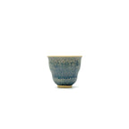 Ceramic cup with blue speckled pattern on a white background