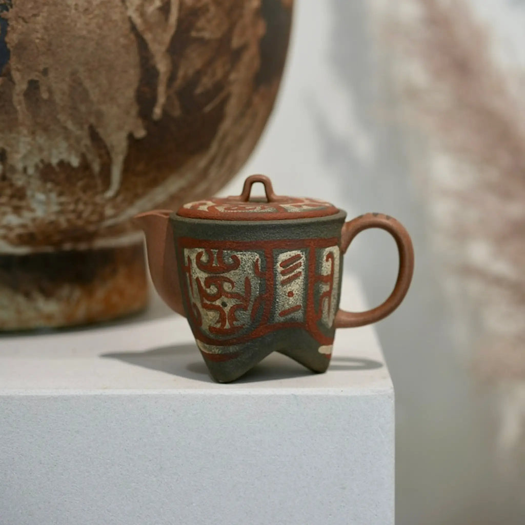 Close-up Cloud & Thunder Yixing teapot standing next to a wabi-sabi style vase, highlighting the intricate hand-painted geometric fretwork.