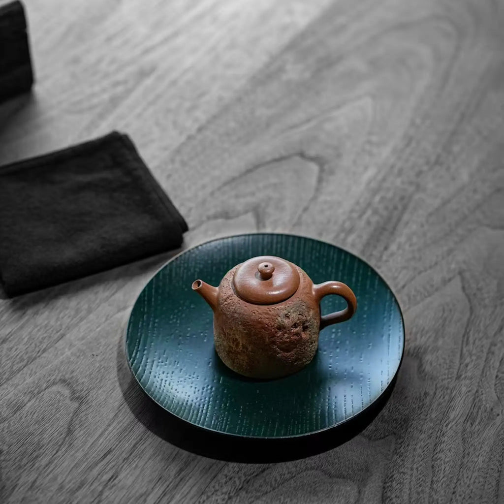 High-angle lifestyle view of the Desert Mirage hand-painted Yixing teapot resting elegantly on a dark wood lacquer tea boat atop a modern tea table.