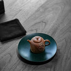 High-angle lifestyle view of the Desert Mirage hand-painted Yixing teapot resting elegantly on a dark wood lacquer tea boat atop a modern tea table.