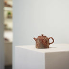 The Desert Mirage painted Yixing Zisha teapot displayed as a work of art, sitting on a minimalist white stand in a contemporary gallery setting.