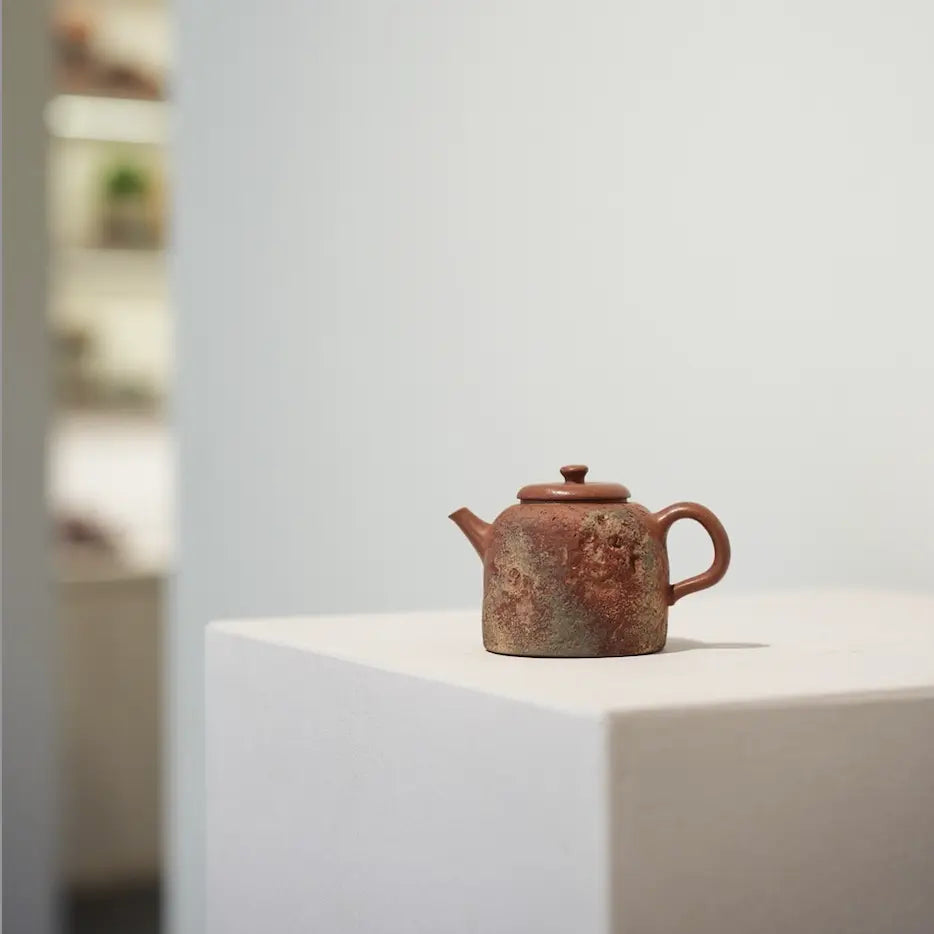 The Desert Mirage painted Yixing Zisha teapot displayed as a work of art, sitting on a minimalist white stand in a contemporary gallery setting.