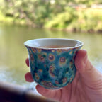 Close-up of the 70ml Aurora Shore Elemental master teacup held gently in hand, filled with steeped tea, showcasing the cup's comfortable proportions and striking artisan glaze in a real-world tasting setting.