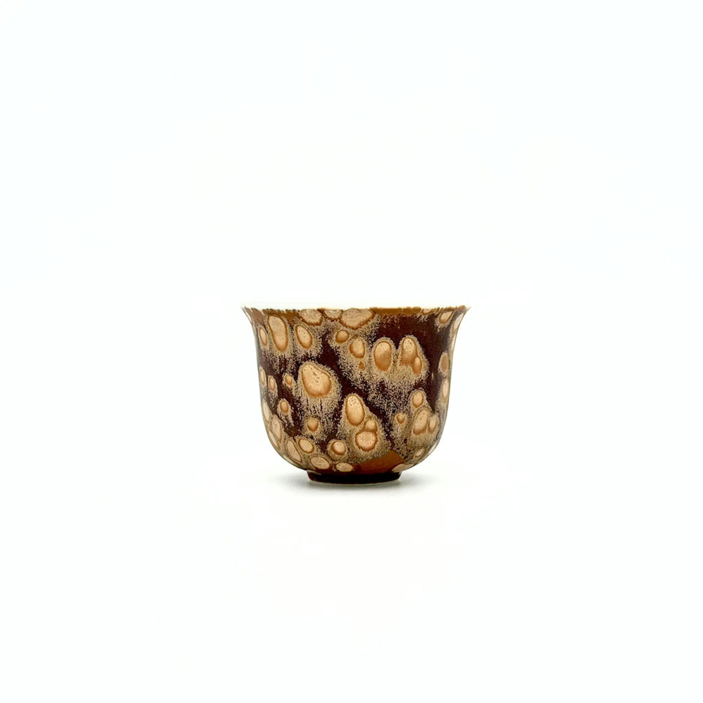 Small ceramic teacup with a unique brown and beige pattern on a white background