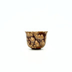 Small ceramic teacup with a unique brown and beige pattern on a white background