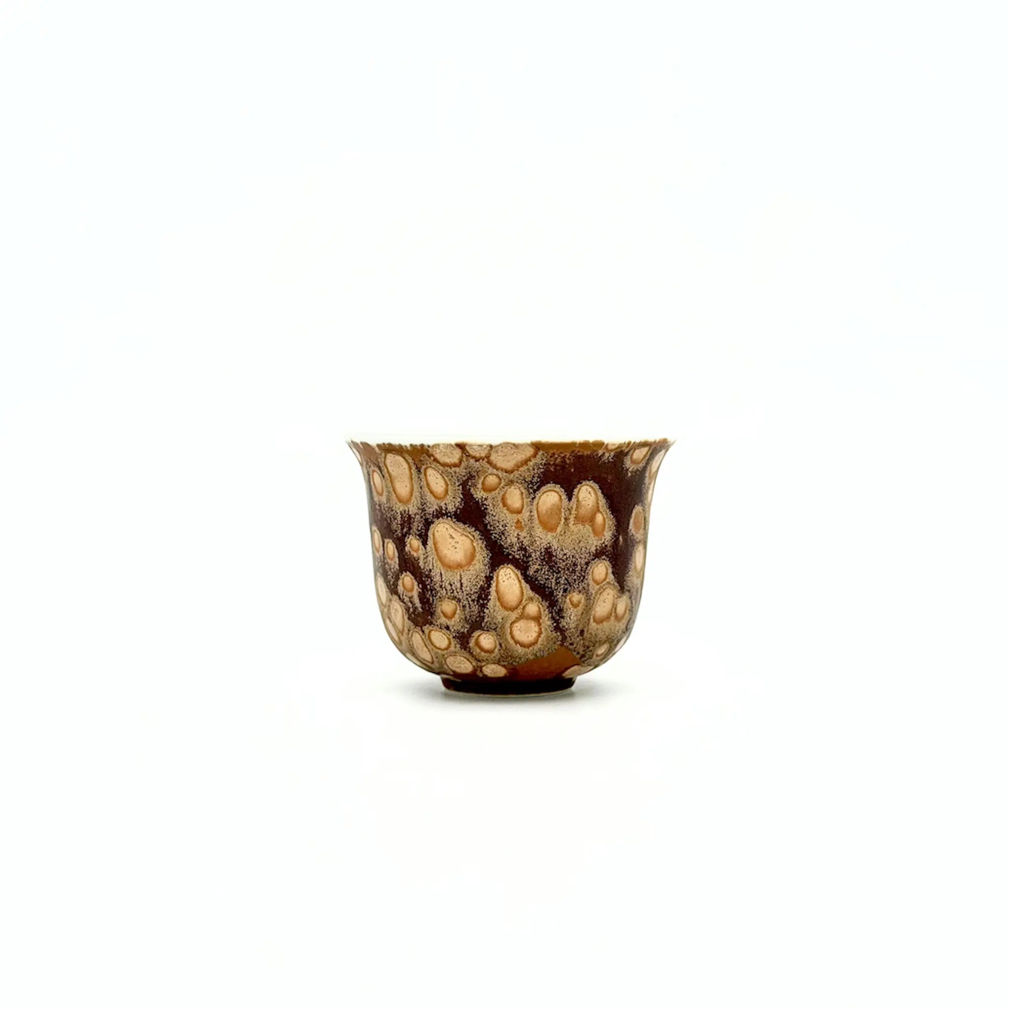 Small ceramic teacup with a unique brown and beige pattern on a white background