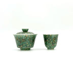 A green glazed ceramic teaware set featuring a lidded bowl with a textured, mottled pattern and a matching small cup, displayed on a clean white background.