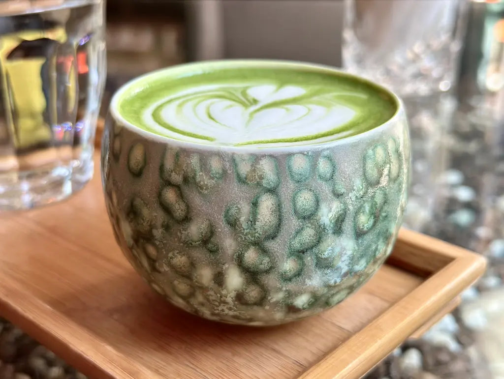 Beautiful latte art displayed inside the Glazara Emerald Current matcha latte cup, showcasing the wide café-style bowl cpu and dynamic, ocean-inspired green ceramic glaze.