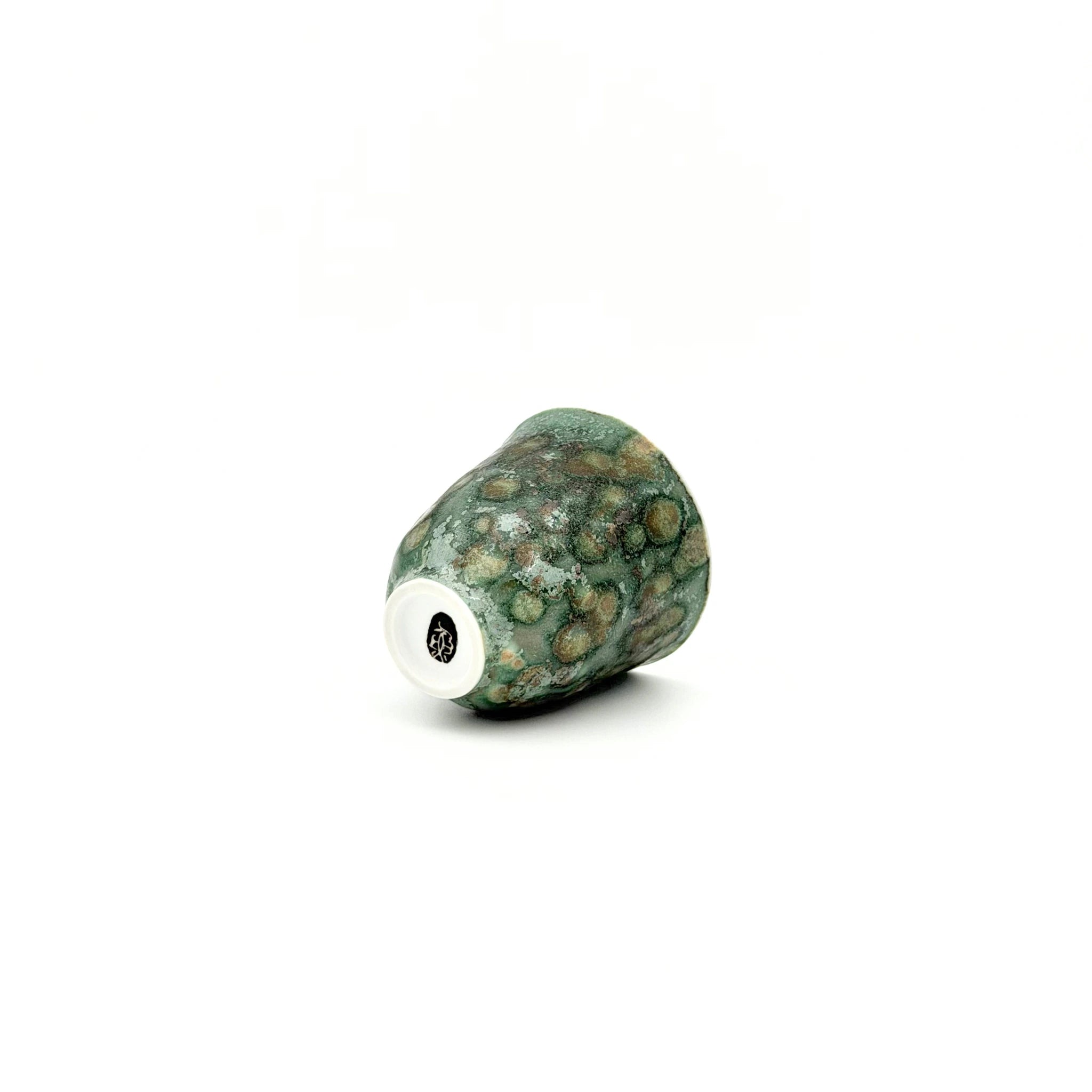 Green textured teacup with artisan's signature at bottom on a white background