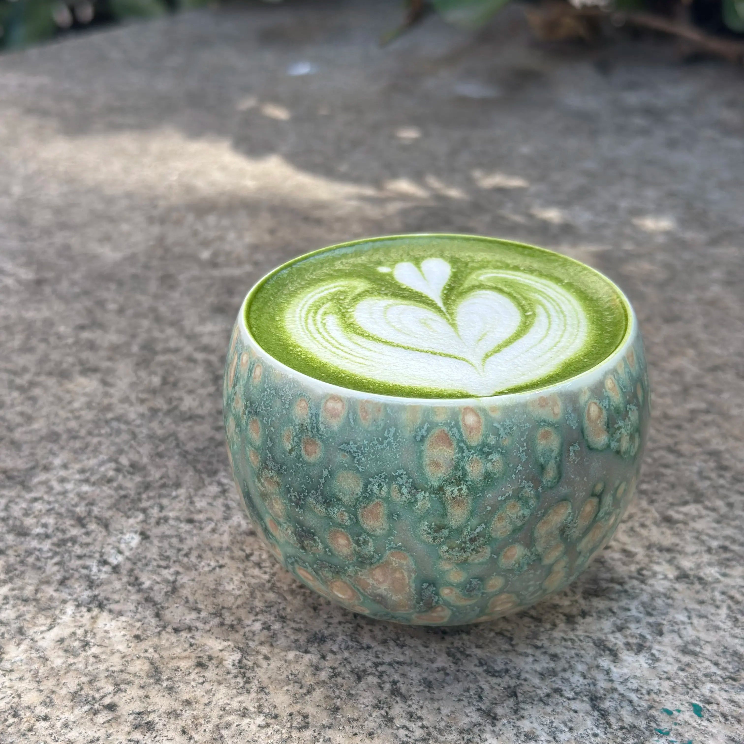 Elegant latte art displayed inside the Glazara Emerald Drift matcha latte cup, highlighting its wide, ergonomic bowl and the rich, flowing green ceramic glaze that beautifully frames the drink.