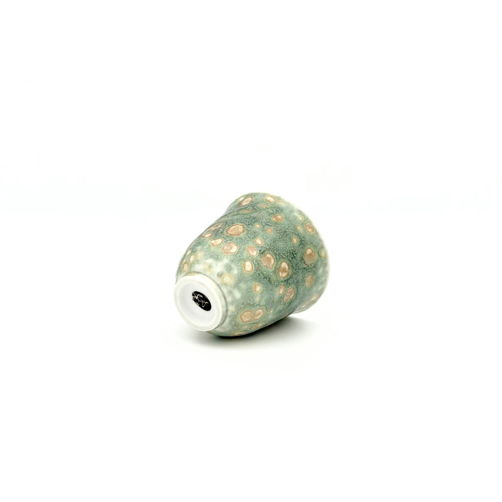 Decorative ceramic teacup with beige speckles on a white background