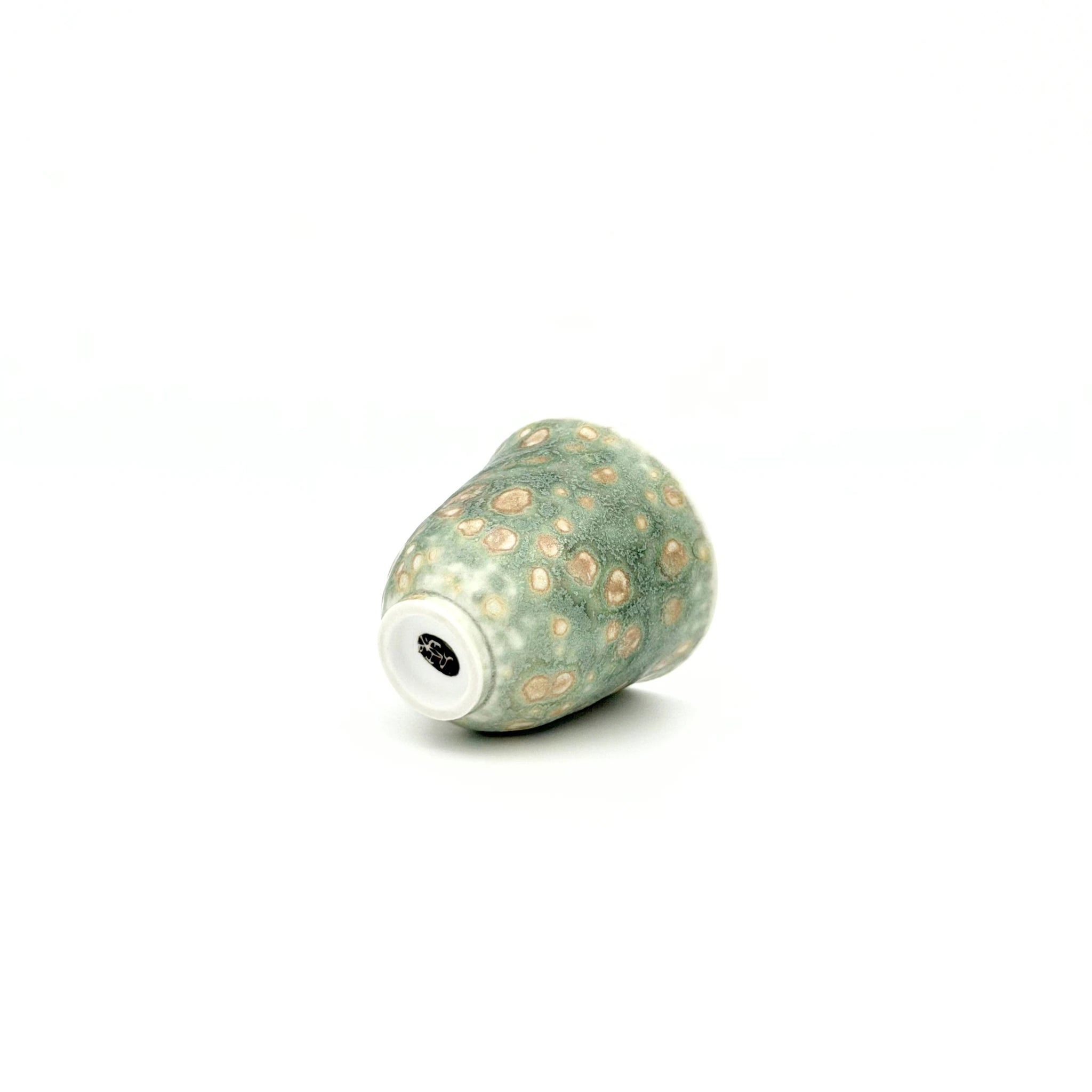 Decorative ceramic teacup with beige speckles on a white background