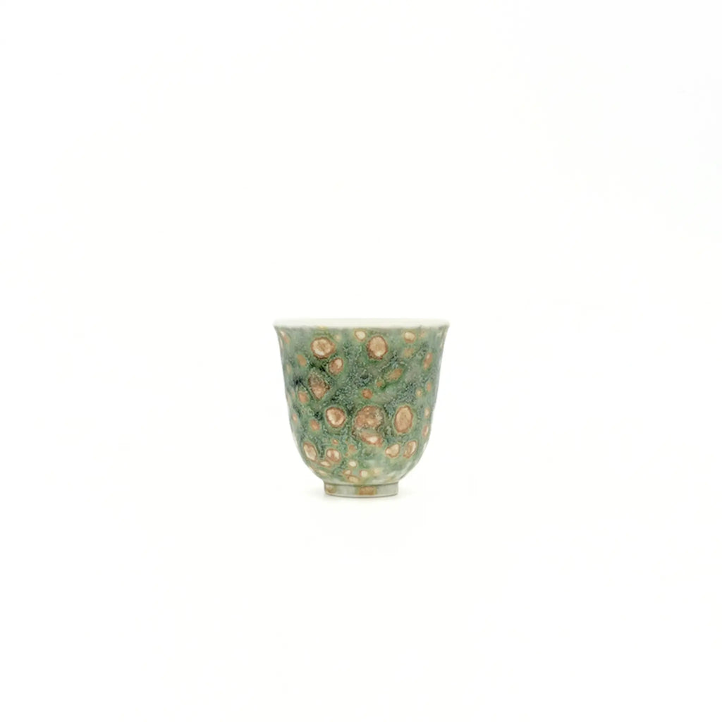 Green ceramic cup with beige speckles on a white background