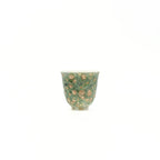 Green ceramic cup with beige speckles on a white background
