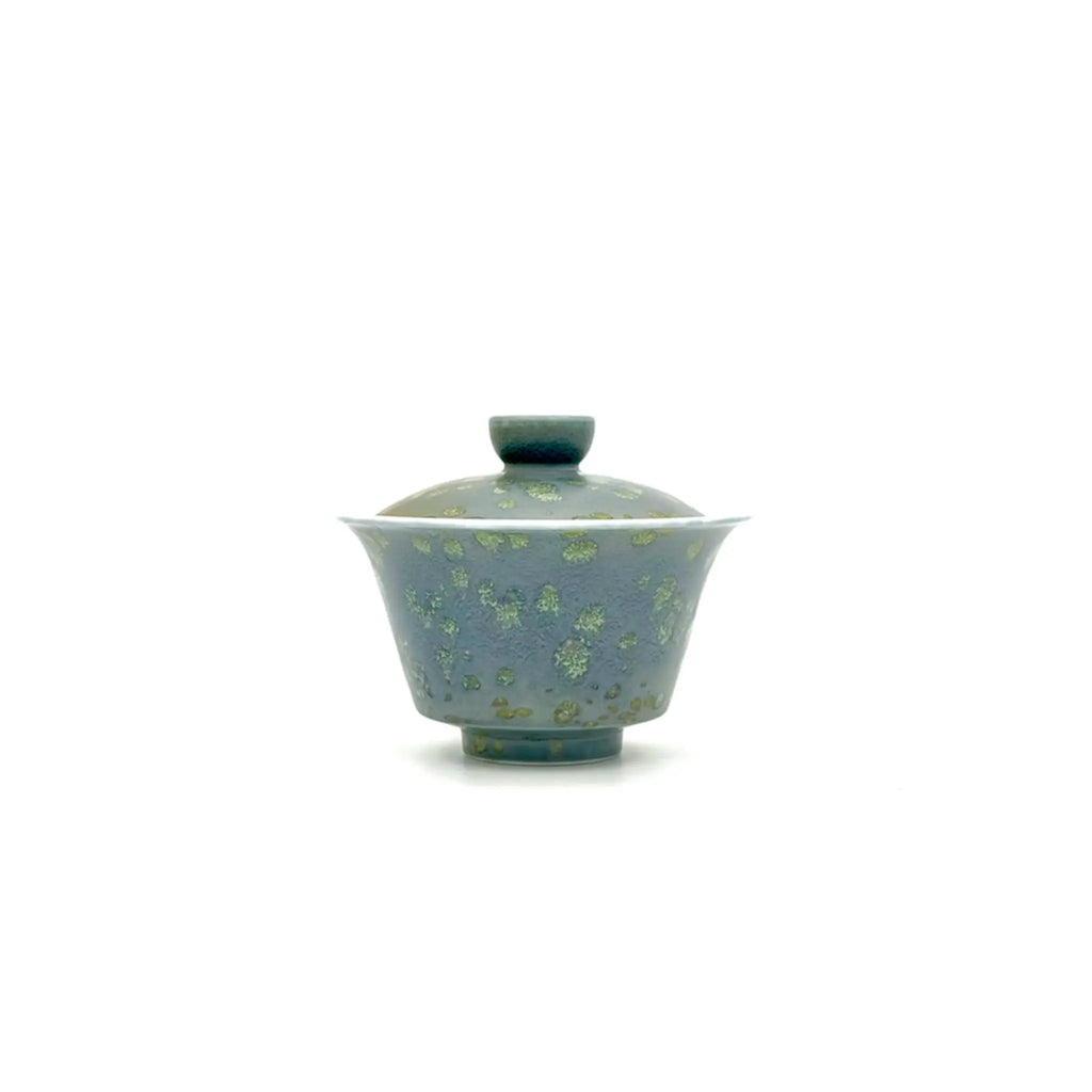 A traditional Chinese gaiwan tea bowl with a matching lid, featuring a speckled blue-green and green glaze on a plain white background.