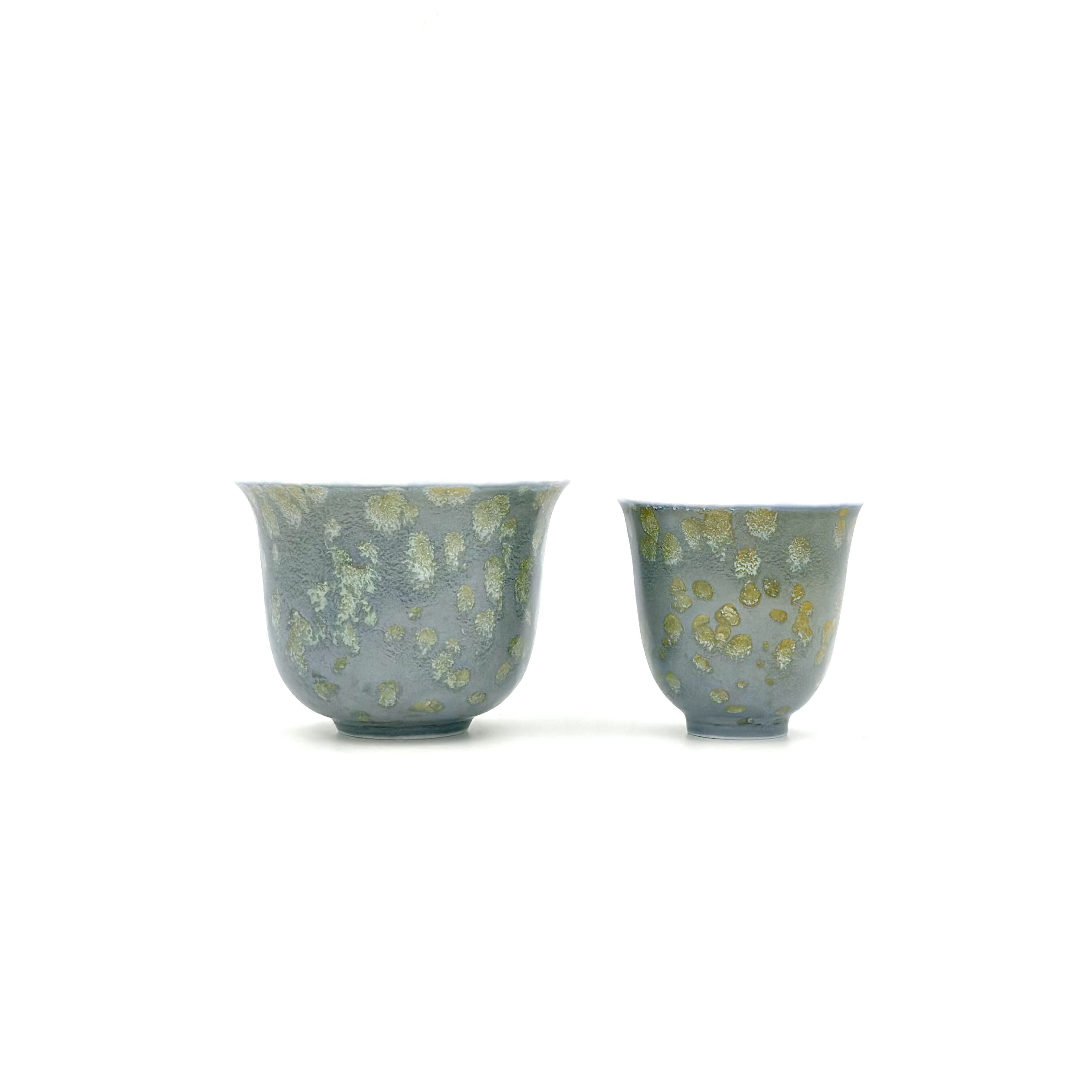 A front-view size and shape comparison between the larger Glazara Giverny Ripple host teacup and the smaller 30ml tasting teacup, showcasing their matching aquatic, water-lily-inspired glazes.