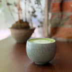 Ceramic cup with green pattern on a wooden surface with blurred background