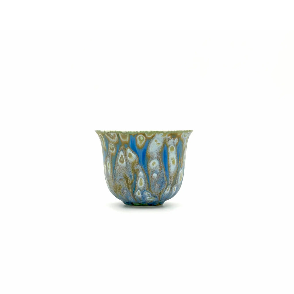 Decorative porcelain teacup with blue and gold patterns on a white background