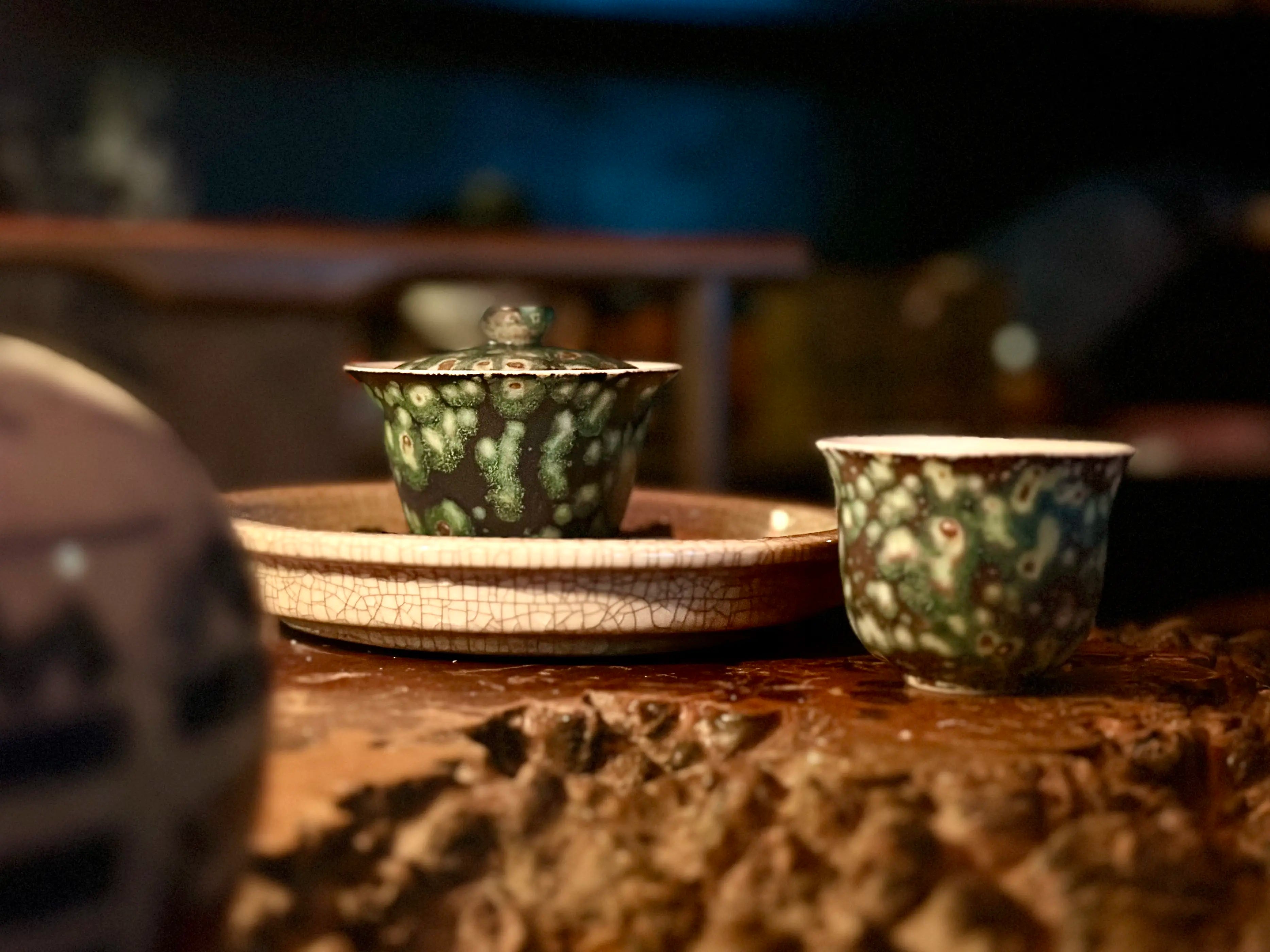 Midsummer Night Gongfu tea set setup: 90ml Gaiwan and matching master teacup resting on a serving tray. Displays the dark, elegant silhouette against a wooden tea table setting.