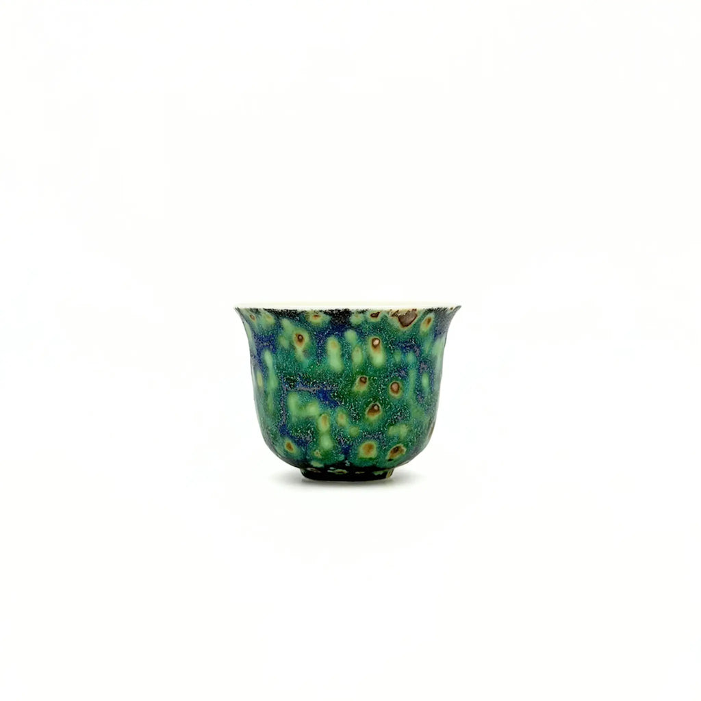 Ceramic teacup with a speckled design on a white background