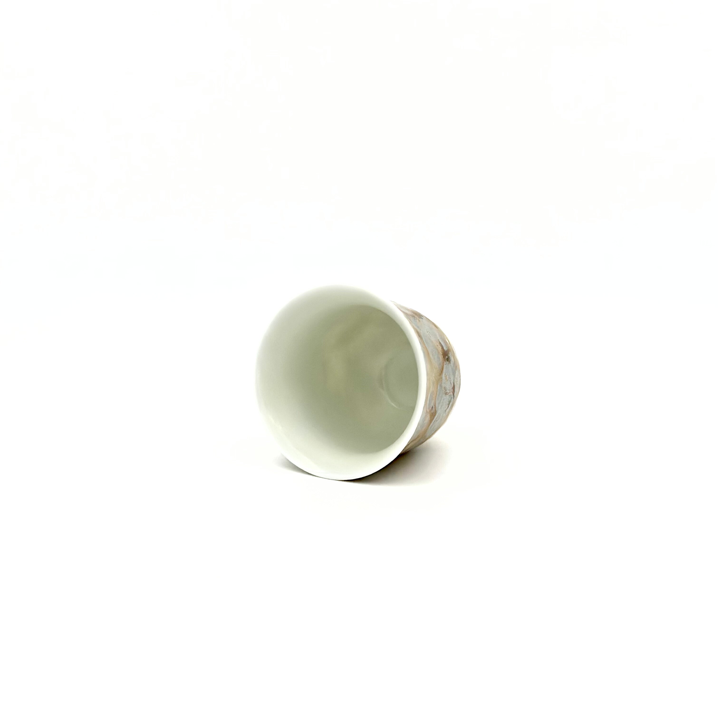Overhead view into the smooth, white interior of the 30ml Glazara Morning Shimmer porcelain teacup, expertly glazed to perfectly reflect the color and clarity of specialty tea liquors.