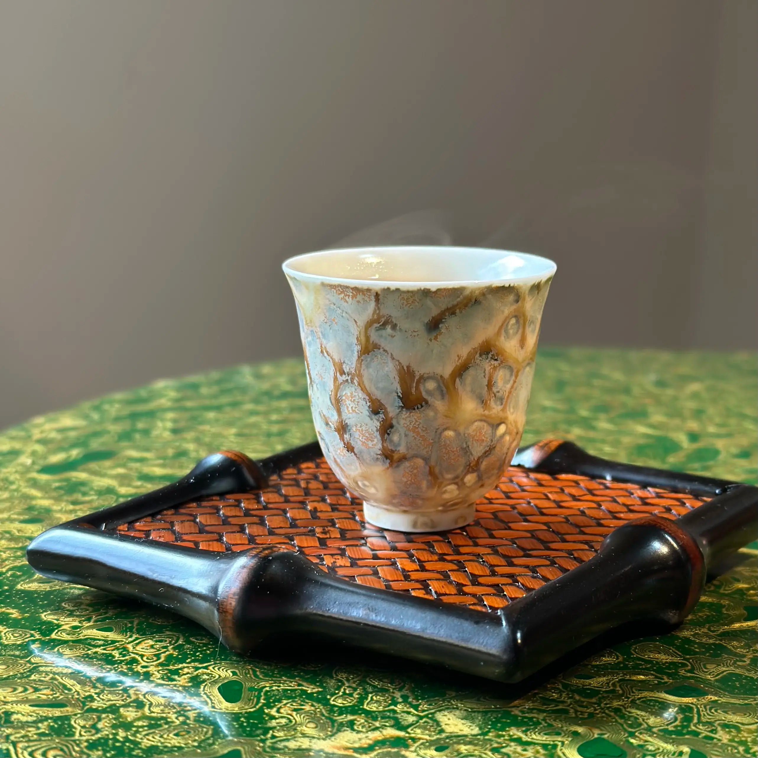 Lifestyle view of the 30ml Glazara Morning Shimmer tasting teacup resting elegantly on a traditional bamboo tea tray, illustrating a beautiful and authentic Gongfu tea ceremony setup.