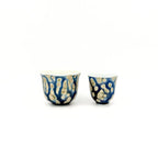 Two ceramic cups with blue and gold patterns on a white background