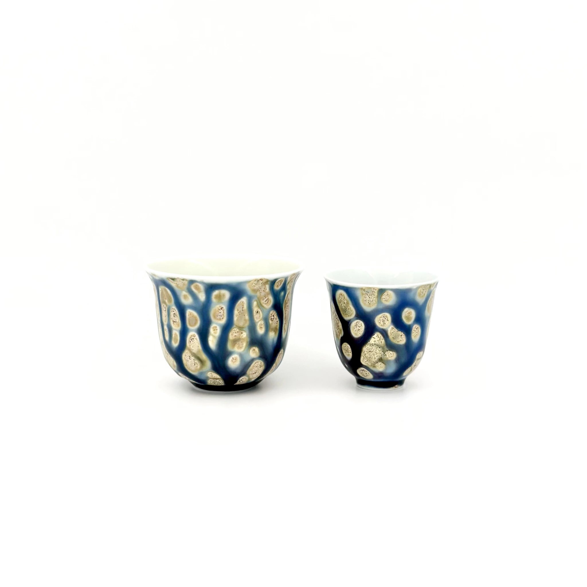 Two ceramic cups with blue and gold patterns on a white background