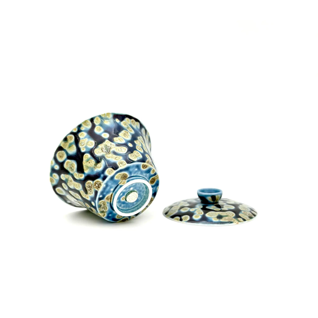 Showcasing the bottom artisan's signature and glaze of a porcelain gaiwan, featuring a decorative pattern on a white background