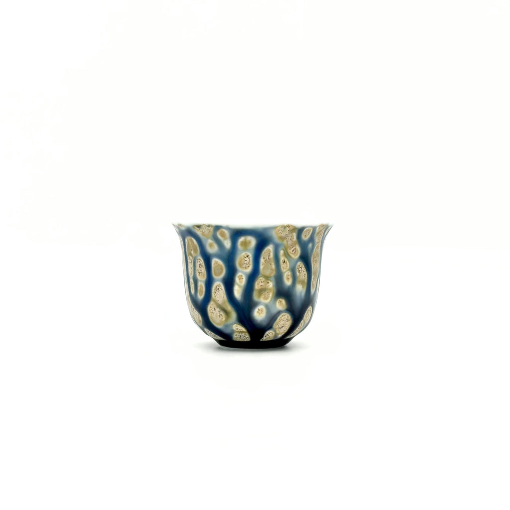 Ceramic cup with blue and gold pattern on a white background