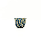 Ceramic cup with blue and gold pattern on a white background