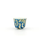 Decorative porcelain teacup with blue and gold pattern on a white background