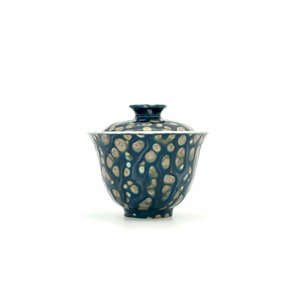 Blue ceramic teapot with white floral patterns on a white background