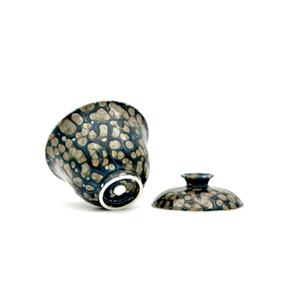 Showcasing the bottom artisan's signature and glaze of a porcelain gaiwan, featuring a decorative pattern on a white background