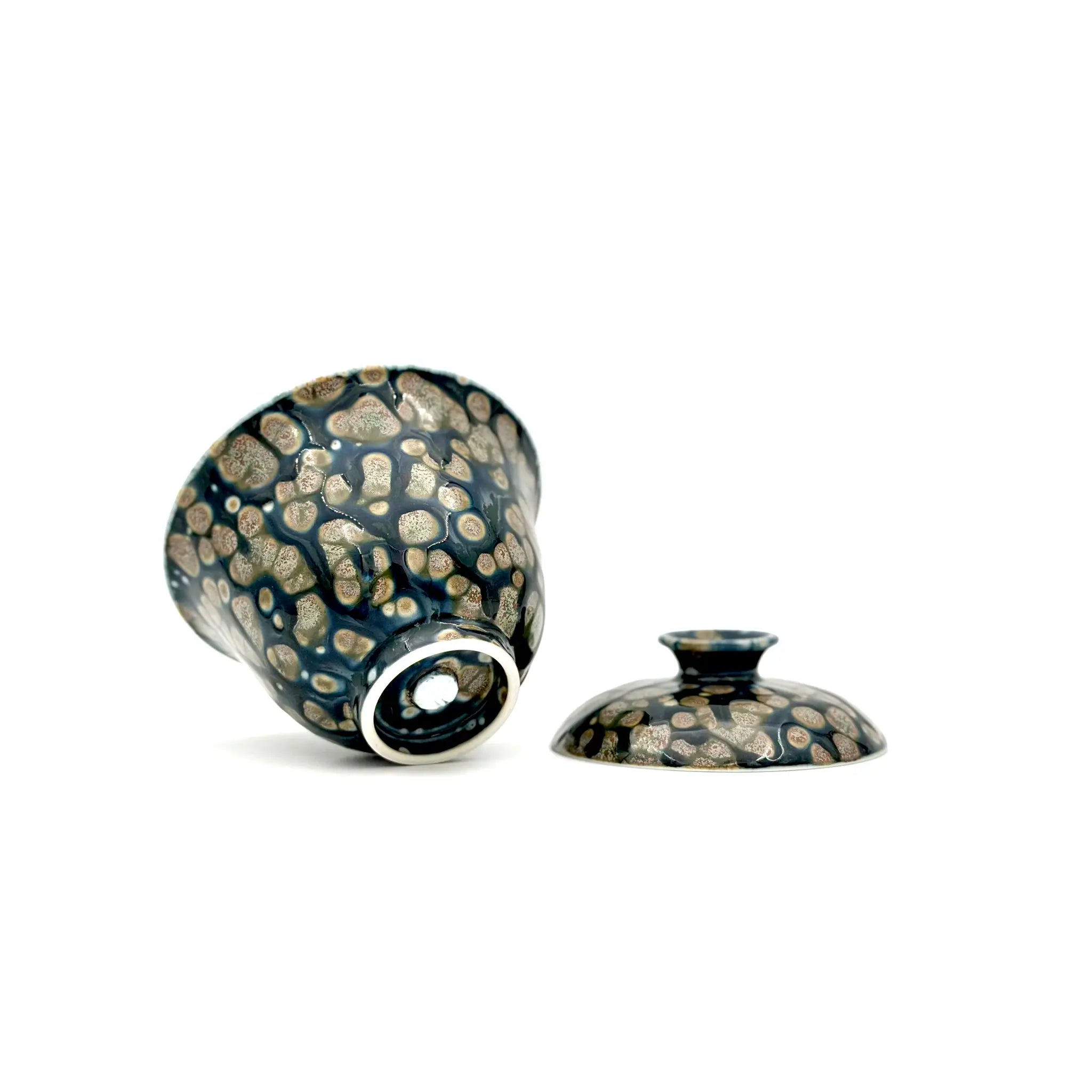Showcasing the bottom artisan's signature and glaze of a porcelain gaiwan, featuring a decorative pattern on a white background