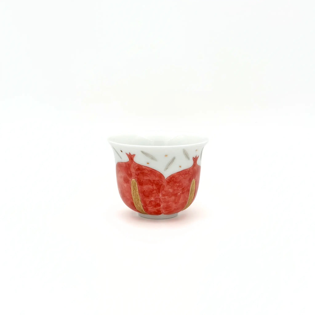 Small ceramic cup with red and gold design on a white background