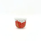 Small ceramic cup with red and gold design on a white background