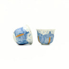 Two ceramic teacups with blue and white design on a white background