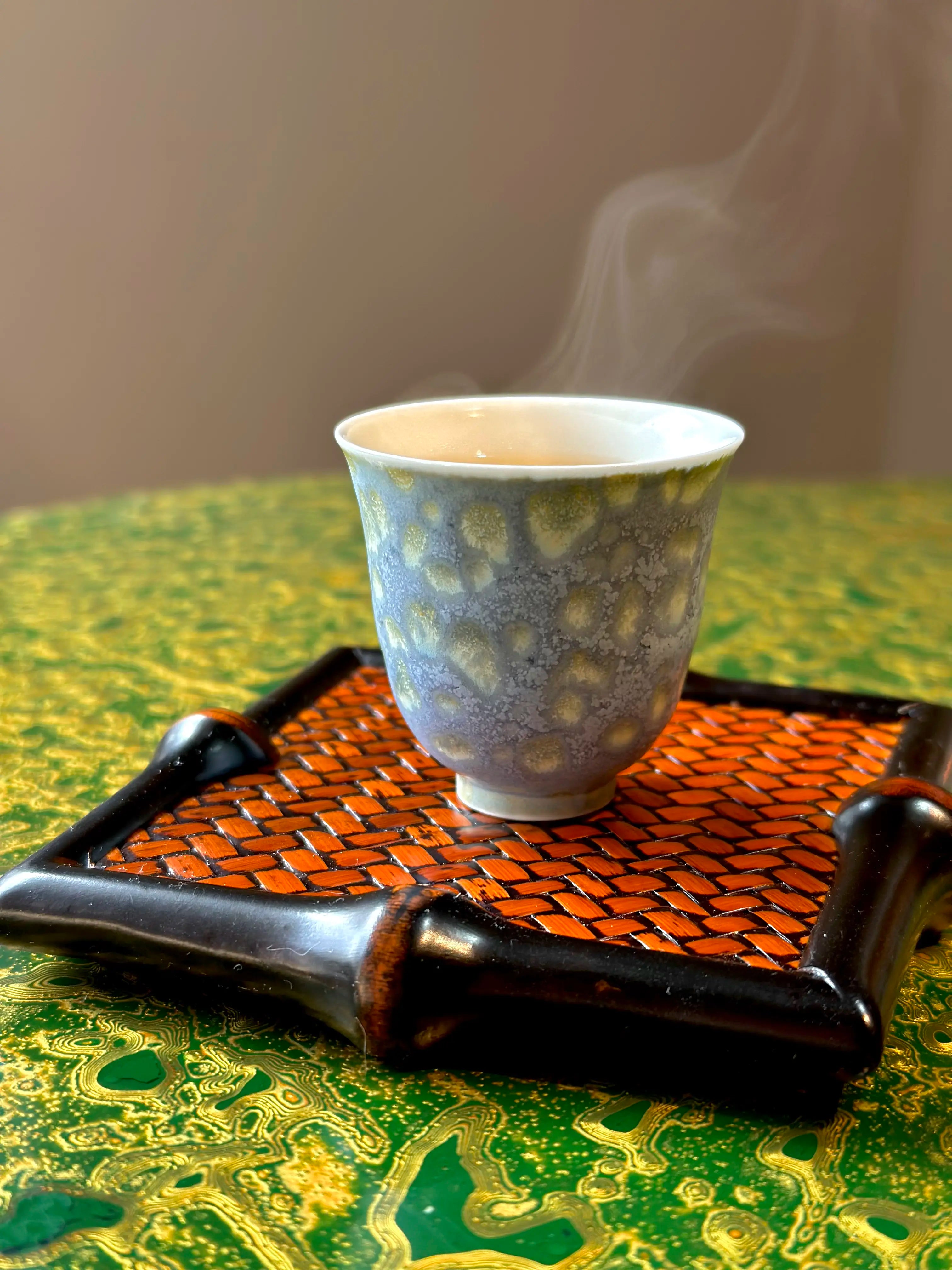 Atmospheric lifestyle view of the 30ml Glazara Promenade Breeze tasting teacup gently steaming on a traditional bamboo tea tray, capturing a serene and authentic Gongfu tea brewing moment.