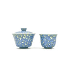 One porcelain gaiwan and one teacup with blue and white speckled pattern on a white background