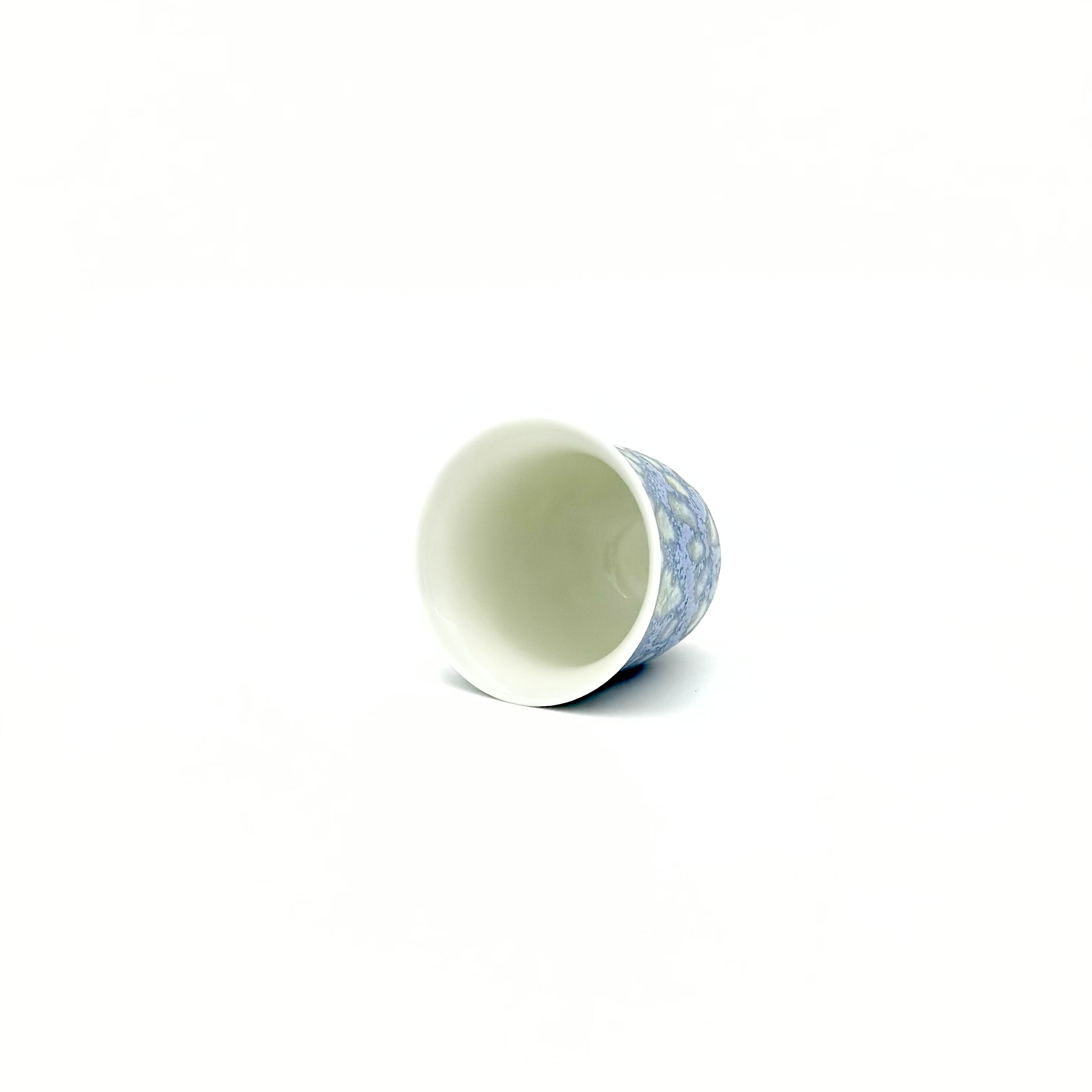 Overhead view into the pristine white interior of the 30ml Glazara Promenade Breeze porcelain teacup, expertly glazed to perfectly reflect the vibrant color and clarity of specialty tea liquors.
