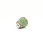 Green ceramic cup with brown speckles on a white background featuring artisan's signature at the bottom.