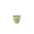 Green ceramic cup with brown speckles on a white background