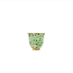 Green ceramic cup with brown speckles on a white background