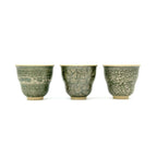 Front view portrait of three 50ml Glazara Verdant Orchid teacups standing side by side, comparing the unique hand-painted Moss Dust, Shattered Ice, and Glacier Crackle green glaze patterns.