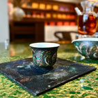 Lifestyle view of the fine porcelain Glazara Viridian Twilight 70ml Gongfu teacup resting gracefully on a lacquer tray, blending modern interior design with fine tea culture.