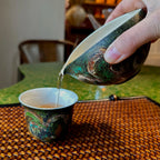 Lifestyle view of pouring tea from the 120ml Glazara Viridian Twilight urushi tea pitcher, a modern porcelain Gongdao Bei designed for Gongfu tea rituals.
